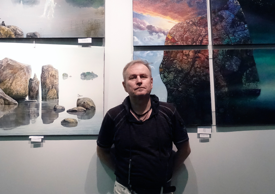 Организатор мероприятия глухой художник Юрий Чернуха на фоне своих картин в выставочном зале Царской башни.